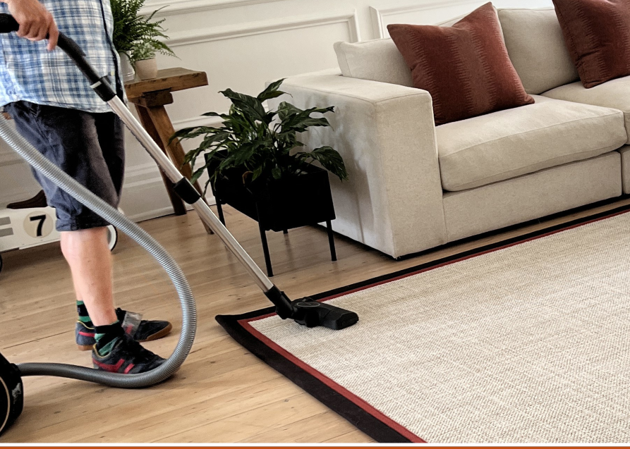 Image showing man hoovering rug, as part of a carpet and rug routine maintenance to keep your carpets and rugs in good condition and lasting longer.